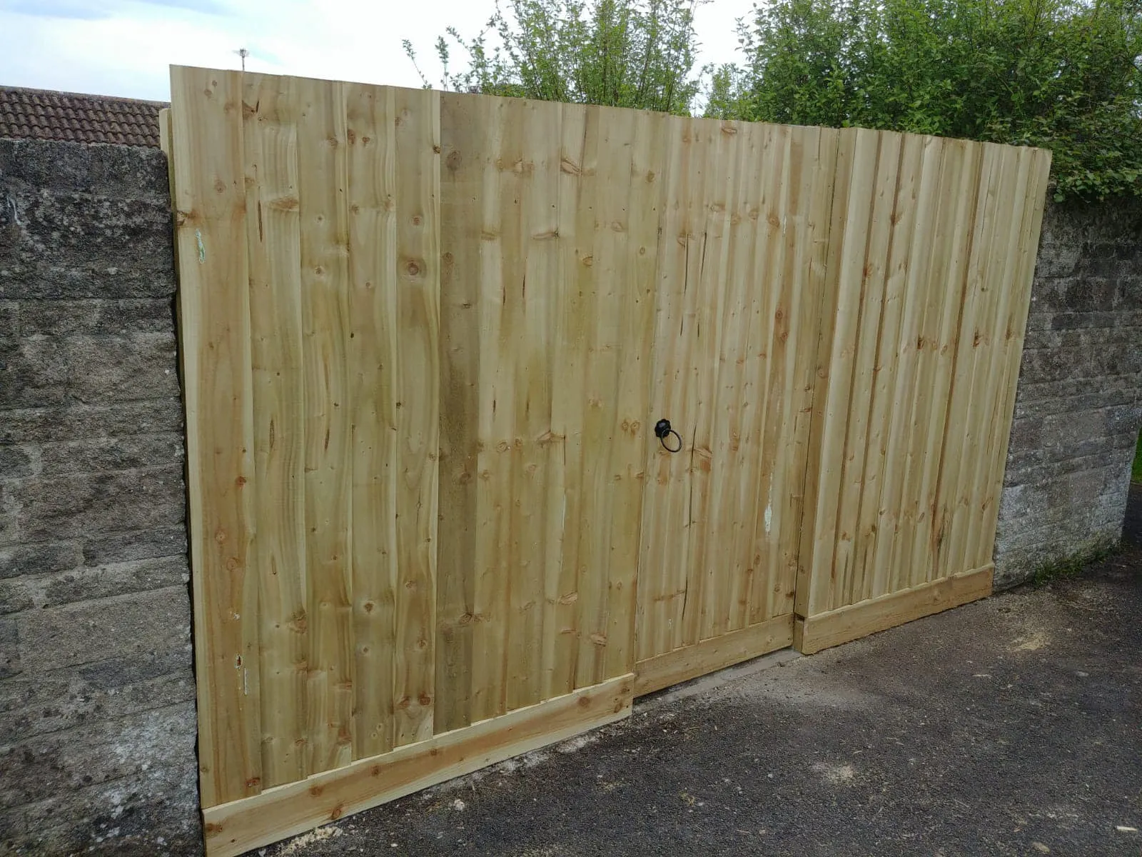 A wooden gate with a brick wall behind it.