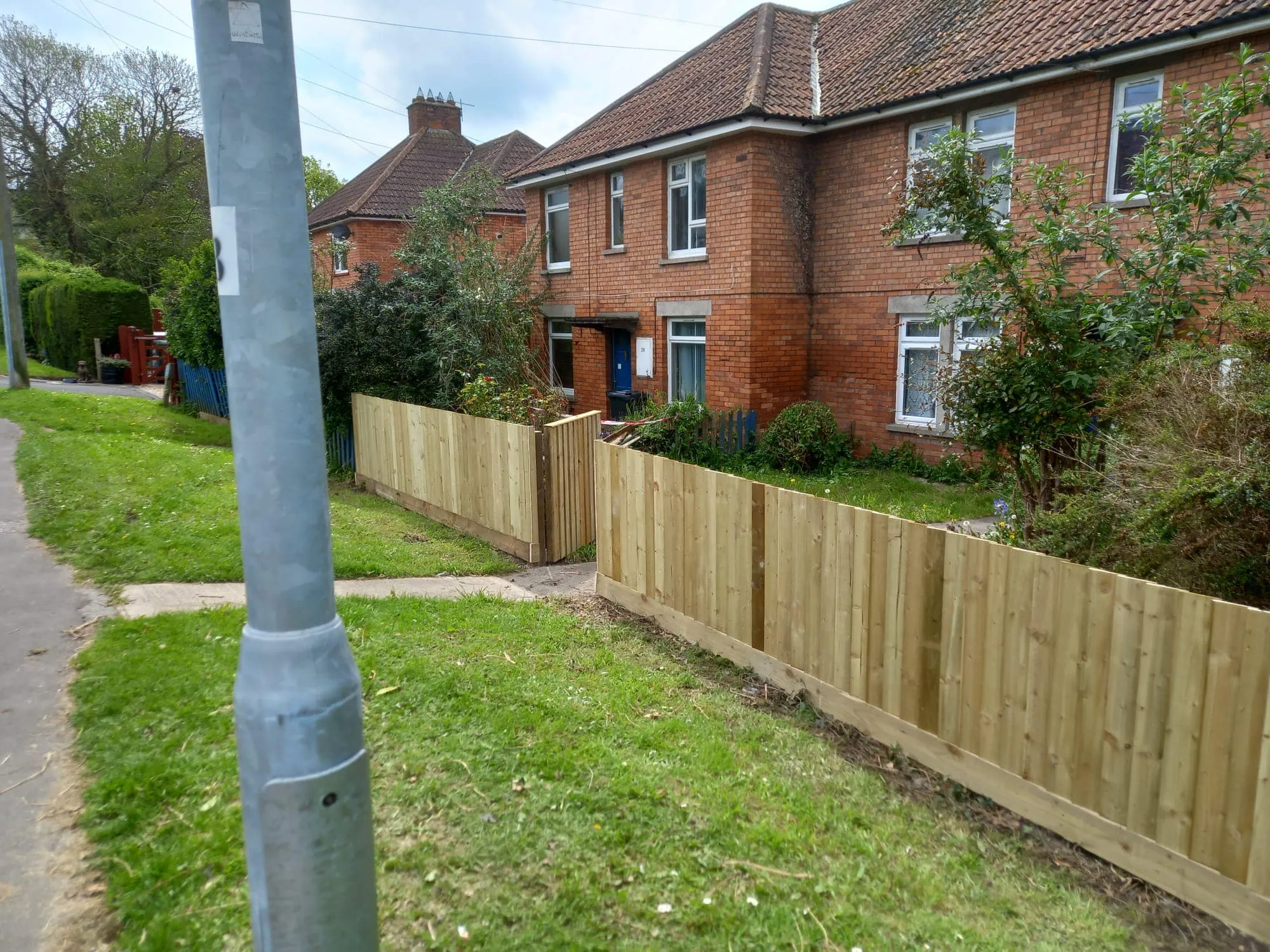 A wooden fence in front of a brick house.