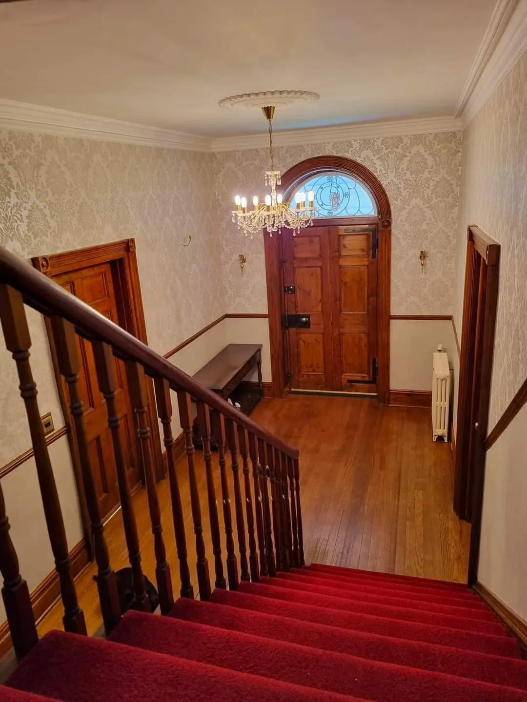 A red carpeted staircase leading to a wooden door.