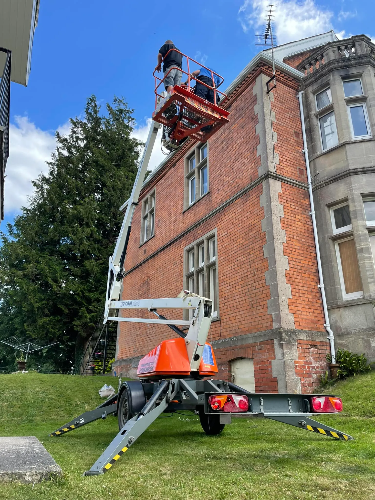 A man on a cherry picker working on a building.